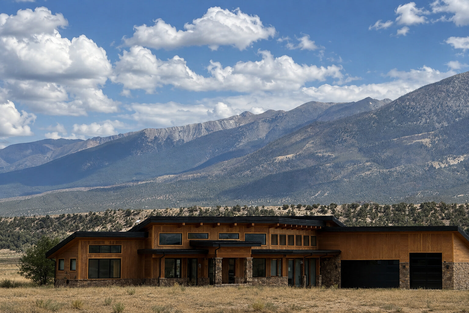 Completed roofline of the Arkansas Valley Residence framed against the Collegiate Peaks and a broad mountain sky.