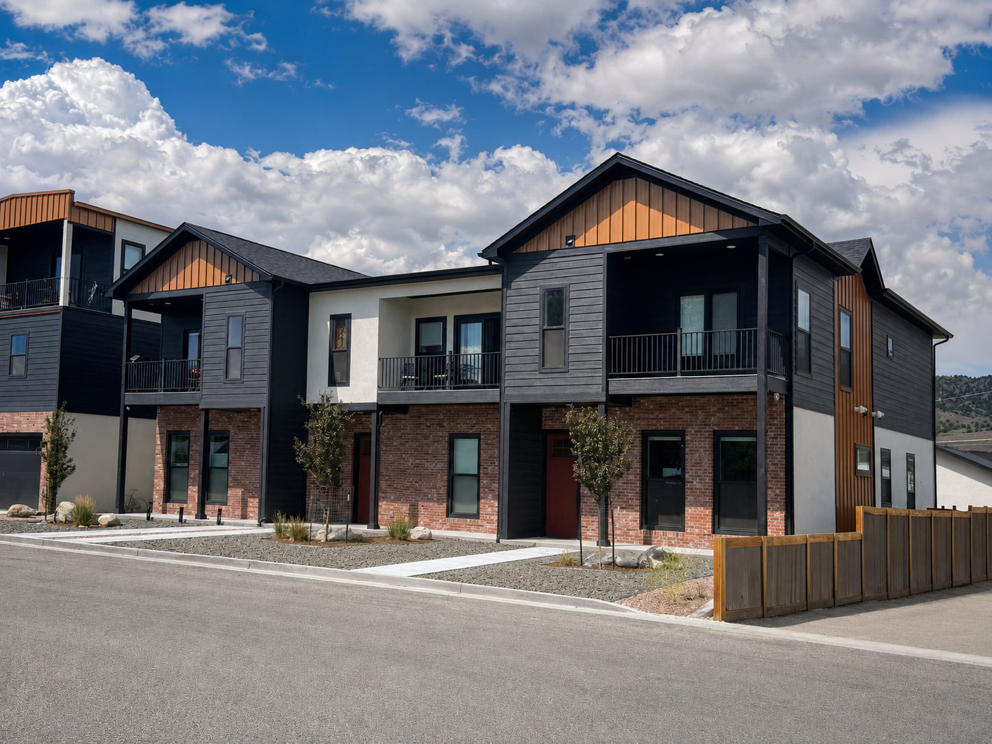 Corner perspective of Brickline Residences showing the end residence, upper porch spaces, layered facade materials, and low-water landscaping.