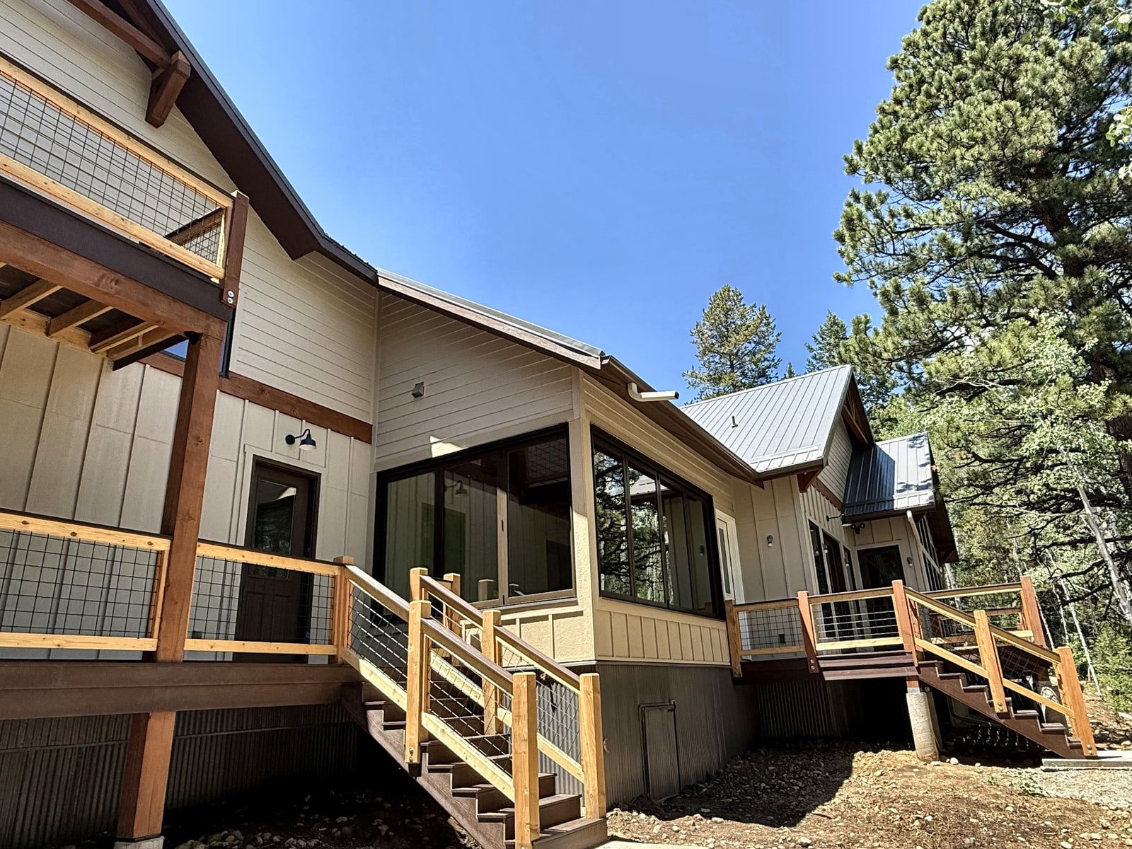 Oblique rear-side view showing multiple decks, exterior stairs, and the home stepping along the hillside.