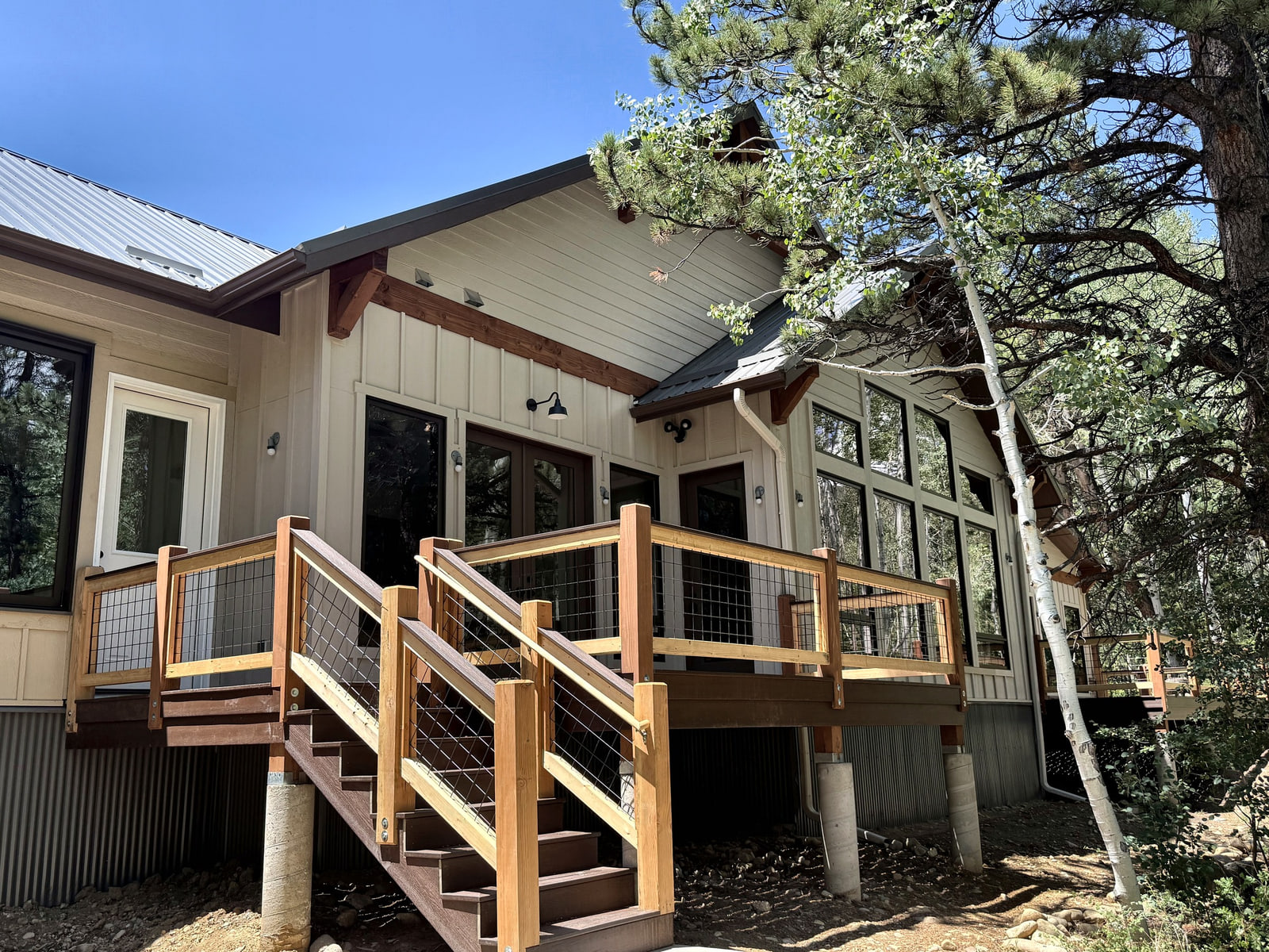 Close exterior view of a timber deck, stair, and entry beneath broad roof overhangs.
