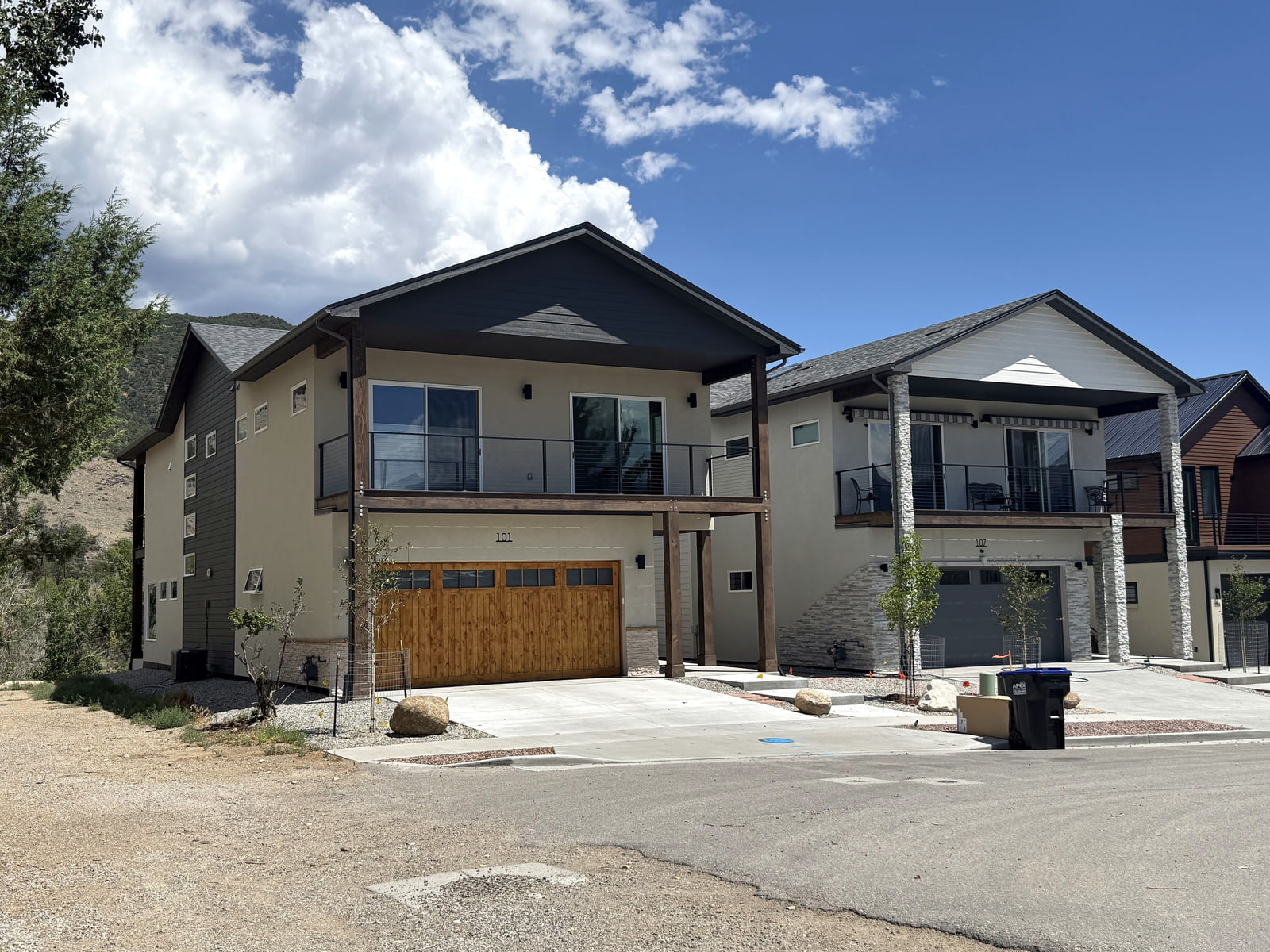 Completed photograph: Two neighboring contemporary homes in Salida with broad second-floor decks and contrasting dark and light gabled facades.