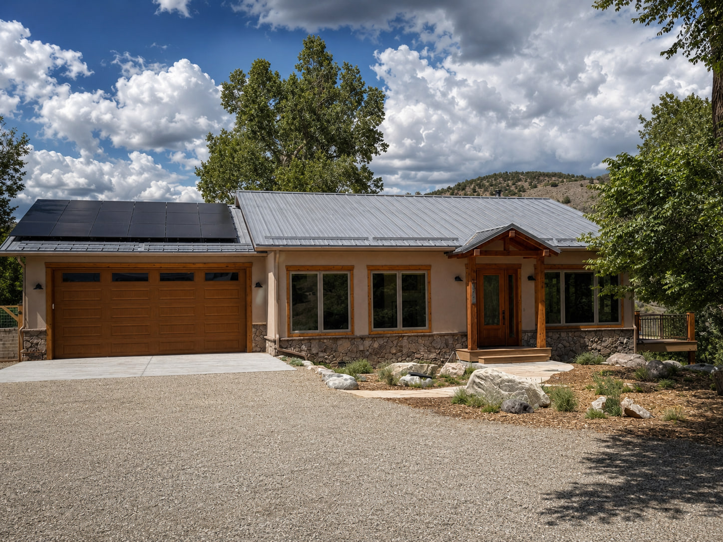 Front exterior of the Riverbend Net-Zero Residence with warm wood detailing, gabled roofs, and a mountain backdrop.