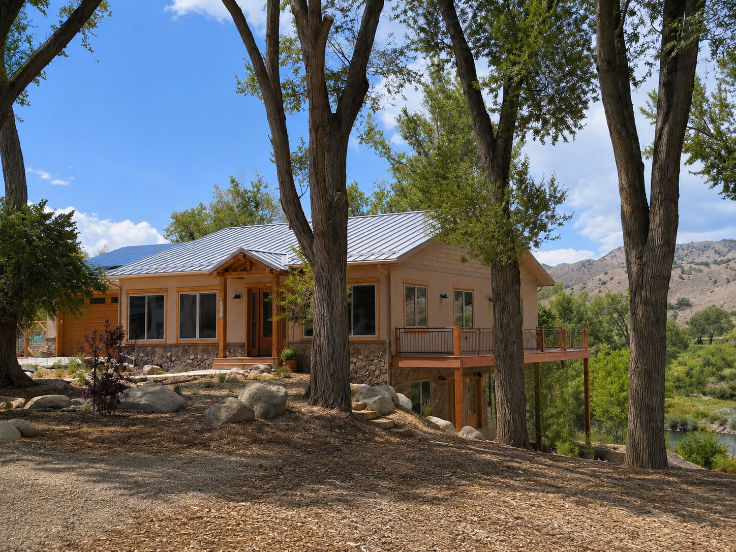 Riverside exterior view showing the home's low roof profile and relationship to the surrounding landscape.