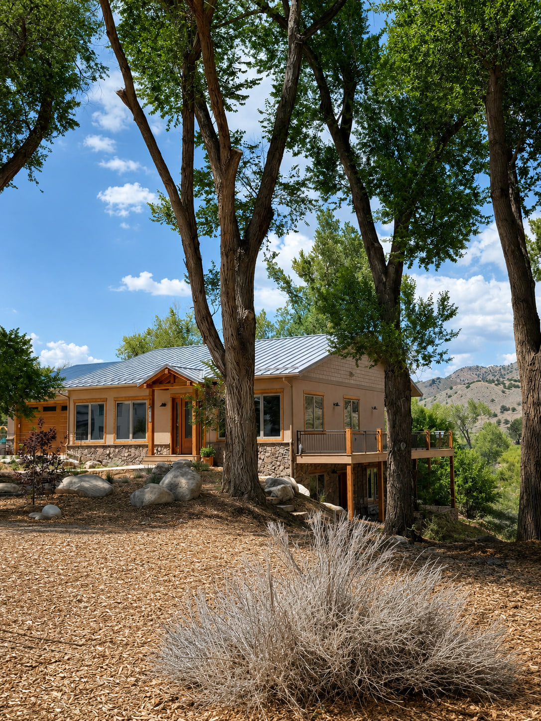 Vertical riverside exterior view framed by mature trees along the Arkansas River.