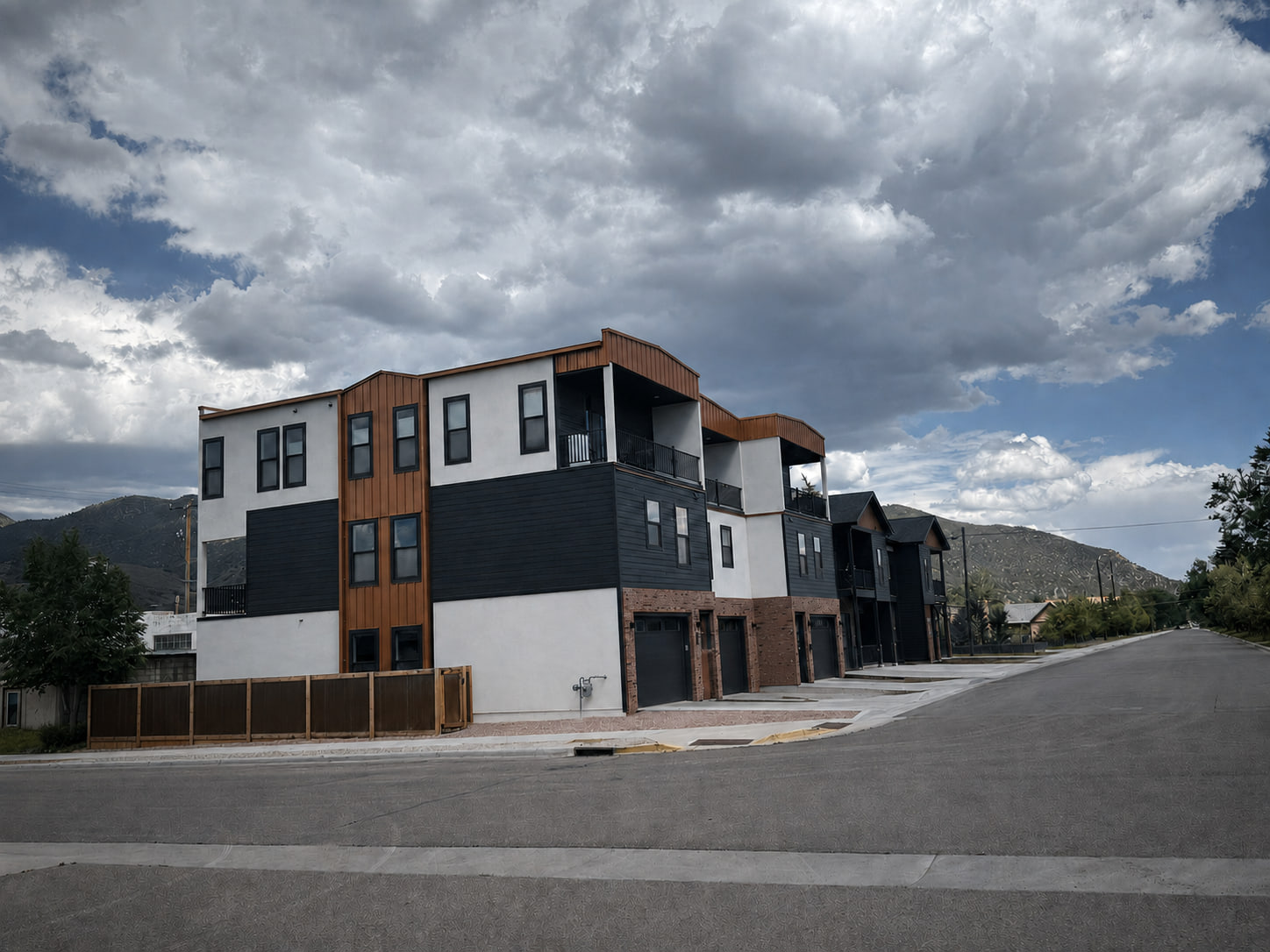 Wide street view of a modern three-story triplex in Salida, Colorado, set within a quiet neighborhood and mountain backdrop.