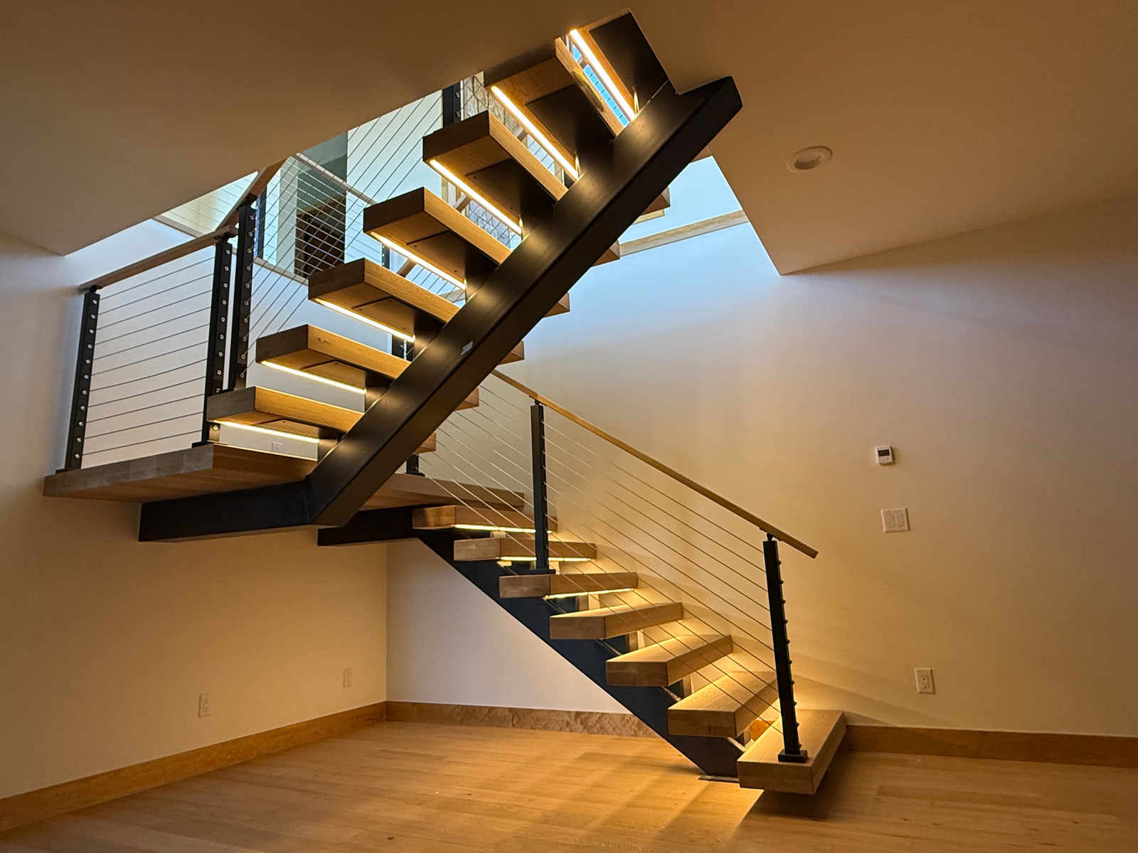 Custom illuminated steel mono-stringer stair connecting the walkout lower level and main floor.