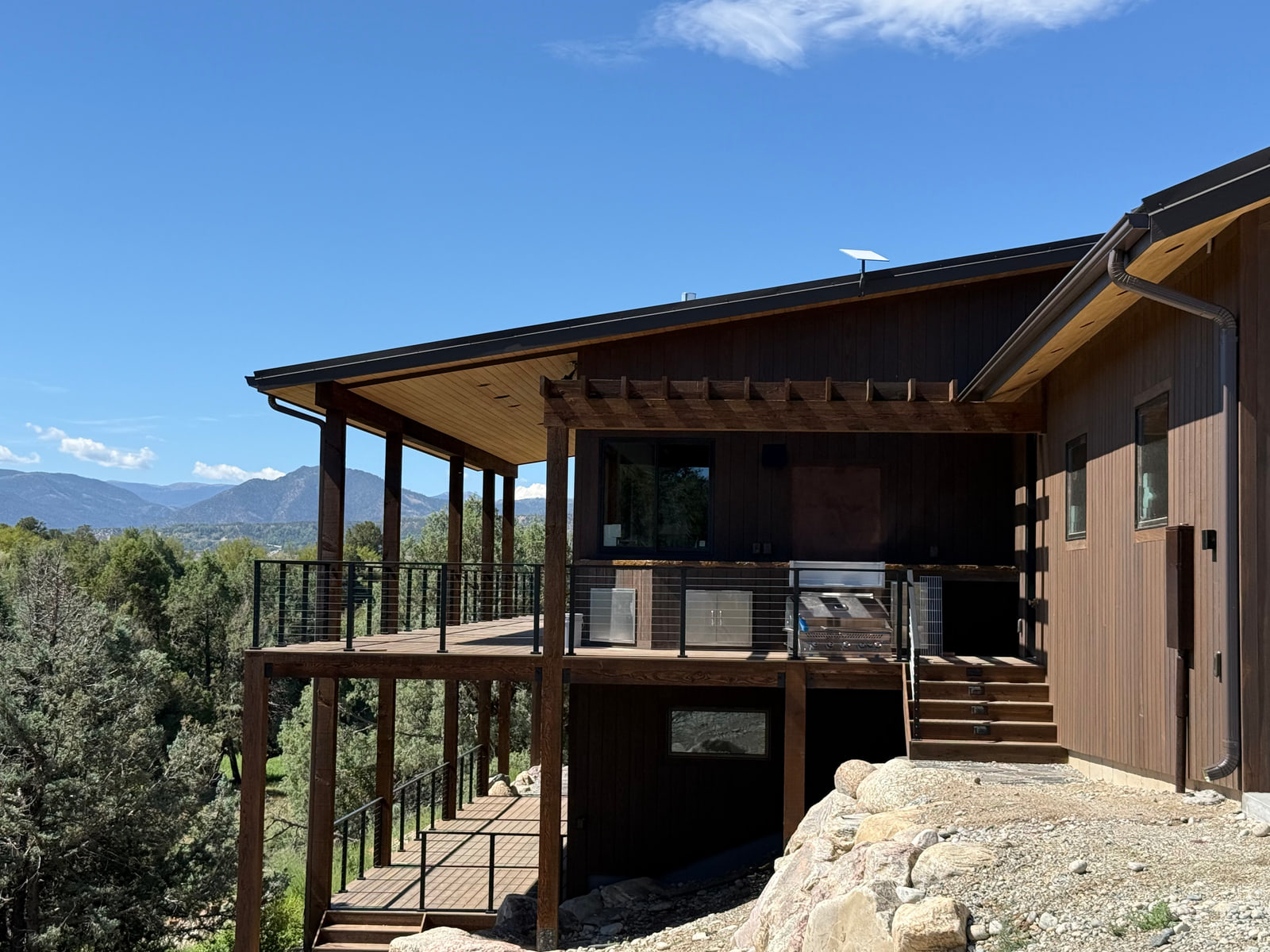Covered outdoor barbecue area with mountain views and access to the walkout level.