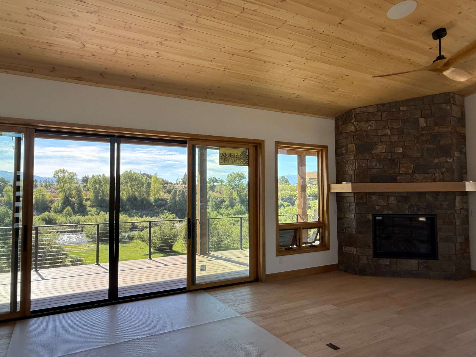 Great room with stone fireplace, large sliding glass doors, and views toward the riverside landscape.
