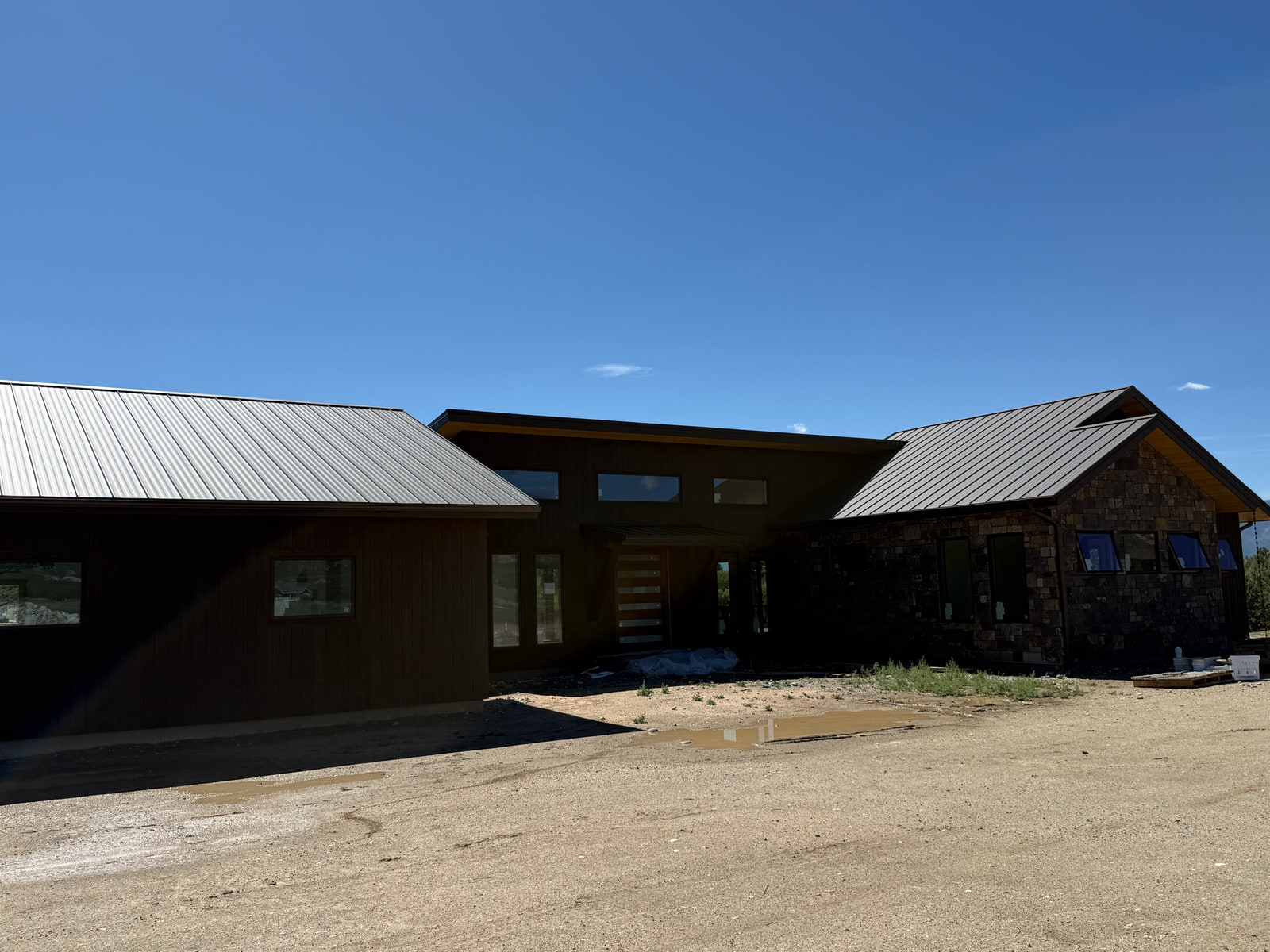 Front approach to Riverside Boathouse Overlook, showing the garage, recessed entry, and stone-clad wing.